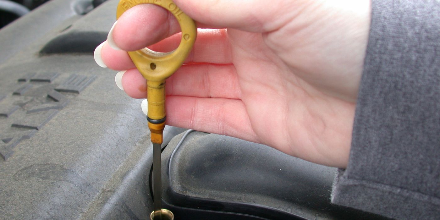Engine oil dipstick being inspected for level and condition during a DIY oil change