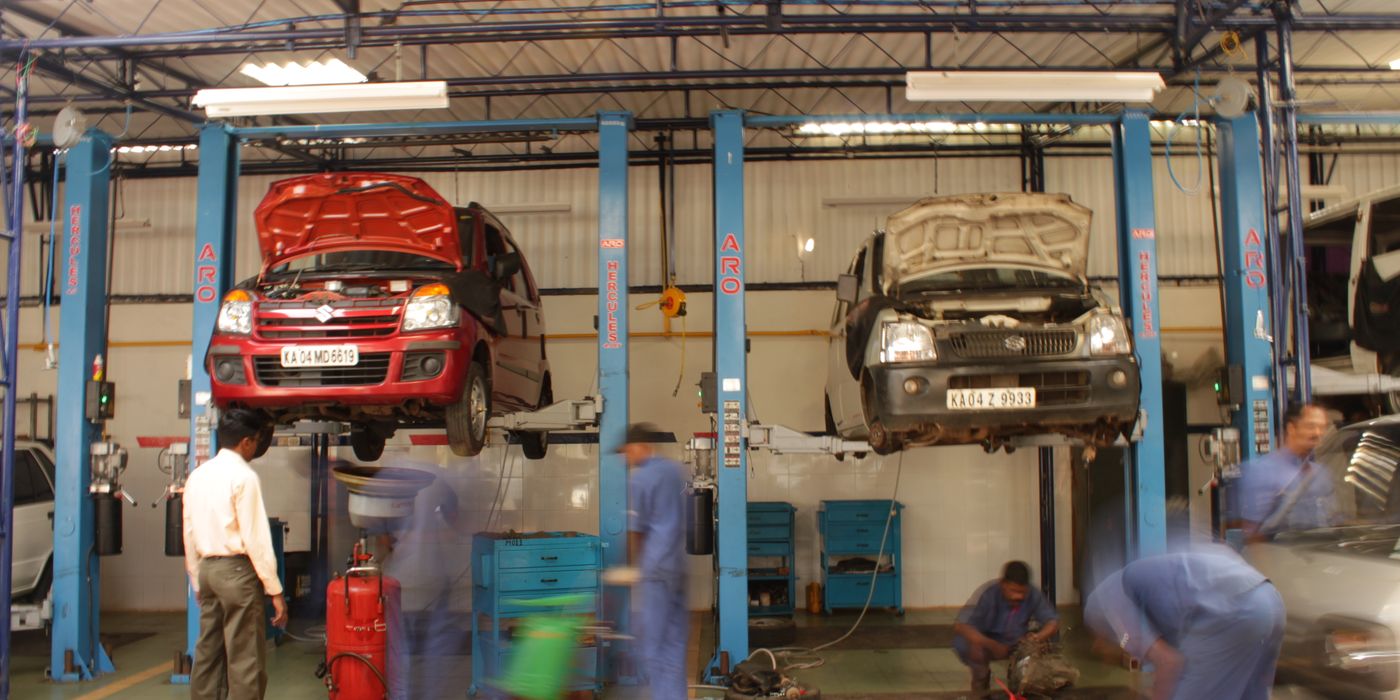 Car raised on a service lift inside an automotive workshop bay with tools and equipment visible