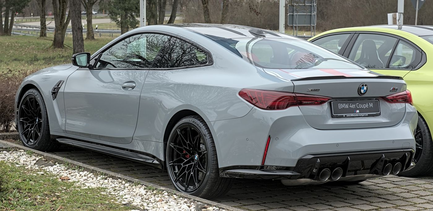 2024 BMW M4 G82 Competition coupe front three-quarter view showing factory forged M wheels and yellow M brake calipers