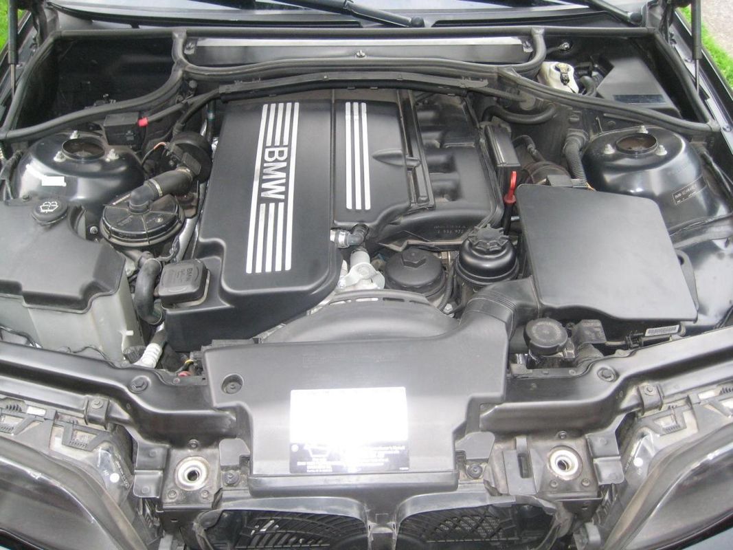 BMW M56 inline-six engine bay showing intake manifold, valve cover and the under-hood positive jump-start terminal location