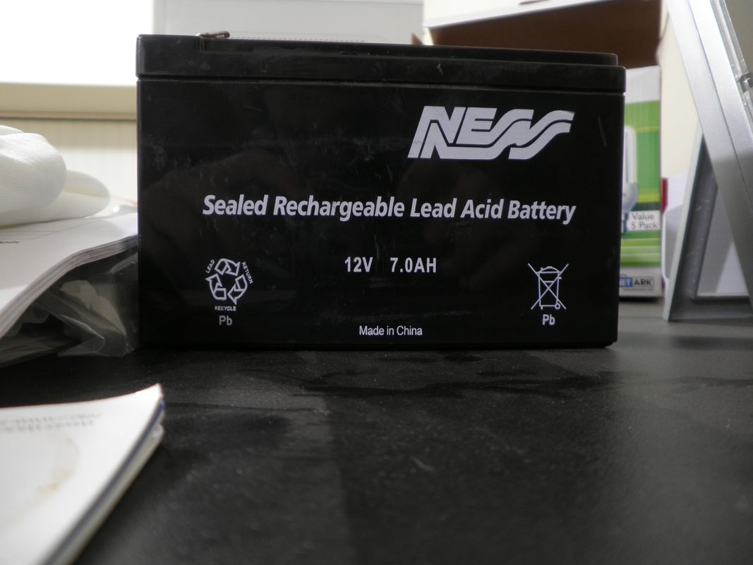 Close-up of a sealed lead-acid 12V automotive starter battery showing positive and negative terminals and carry handles