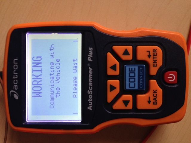 Handheld OBD-II scanner connected to a car diagnostic port, the workflow used to register and code a replacement BMW battery